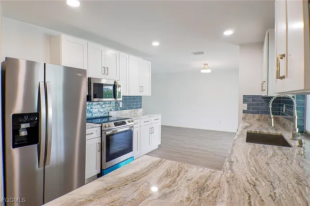 a kitchen with granite countertop a refrigerator and a sink