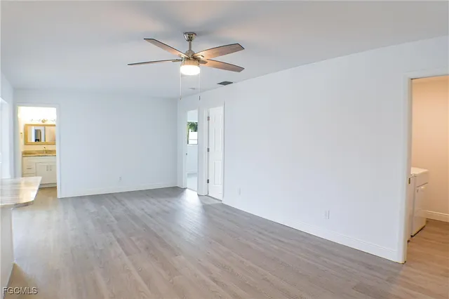 an empty room with wooden floor closet and windows