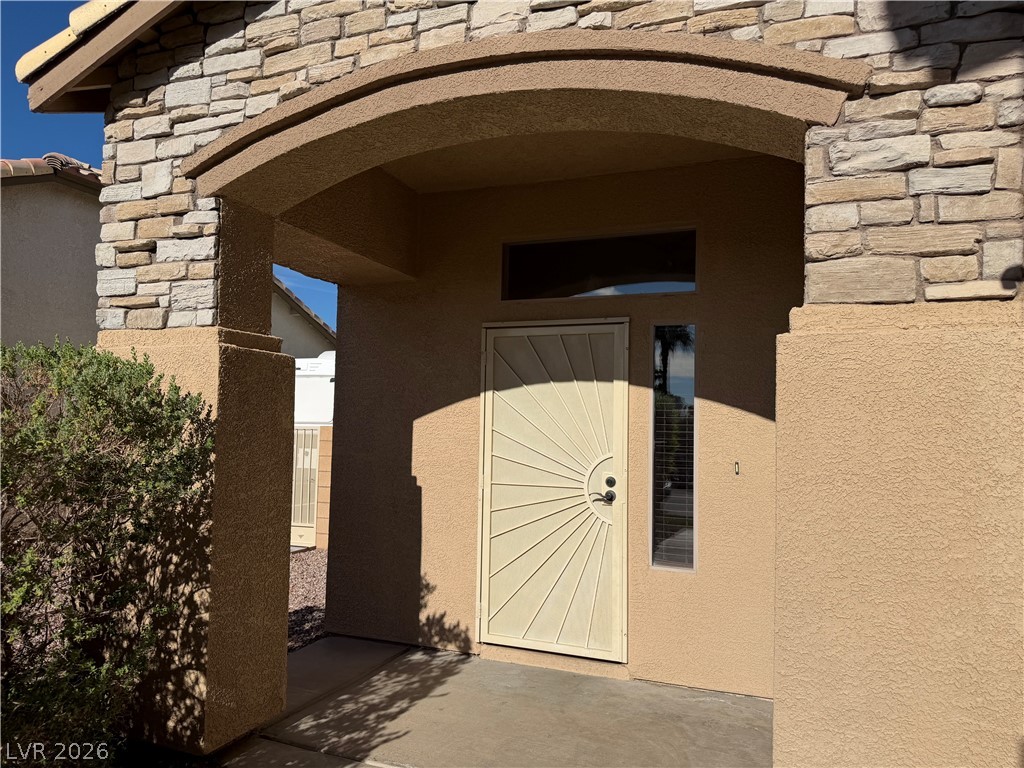 7613 Roop Street Las Vegas, NV 89131 - Photo 3 of 25 An arched covered entry with stone accents welcomes guests to the home.