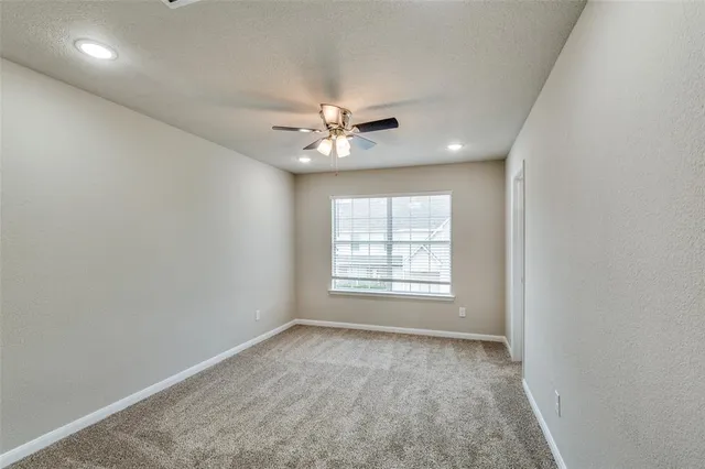 an empty room with windows and ceiling fan