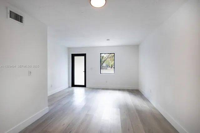 an empty room with wooden floor and windows