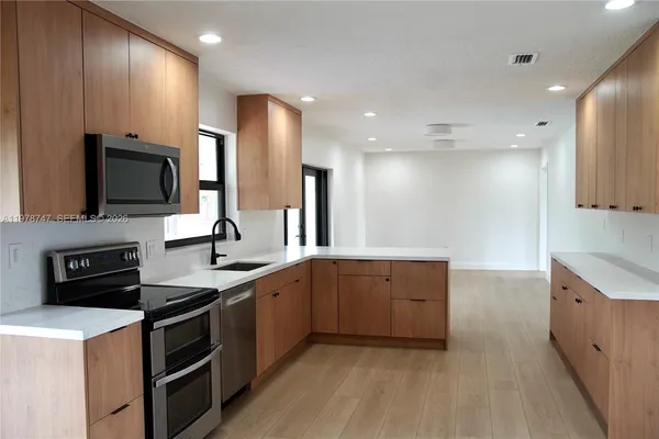 a large kitchen with stainless steel appliances a stove a sink and a microwave