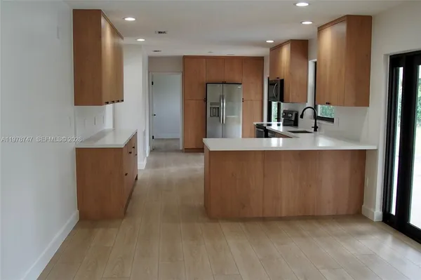a large kitchen with stainless steel appliances a large counter top a refrigerator and a sink