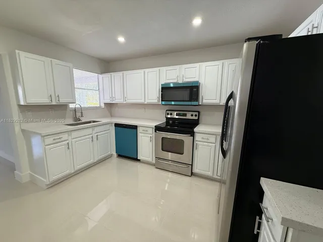 a kitchen with white cabinets and white appliances