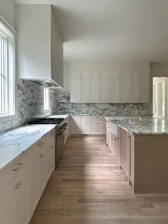 a kitchen with stainless steel appliances granite countertop a stove a sink and white cabinets