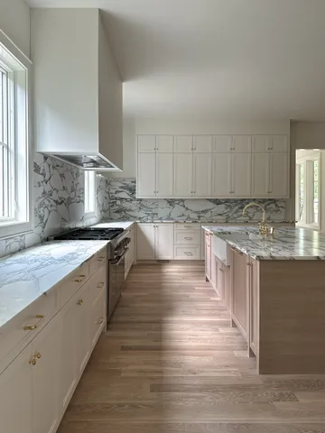 a kitchen with stainless steel appliances granite countertop a stove a sink and white cabinets