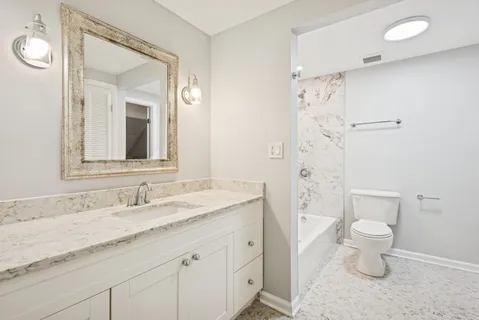 a bathroom with a granite countertop sink a toilet and a mirror