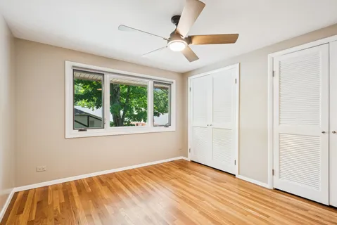 a view of empty room with wooden floor and fan