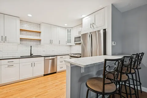 a kitchen with stainless steel appliances granite countertop a table chairs sink refrigerator and cabinets