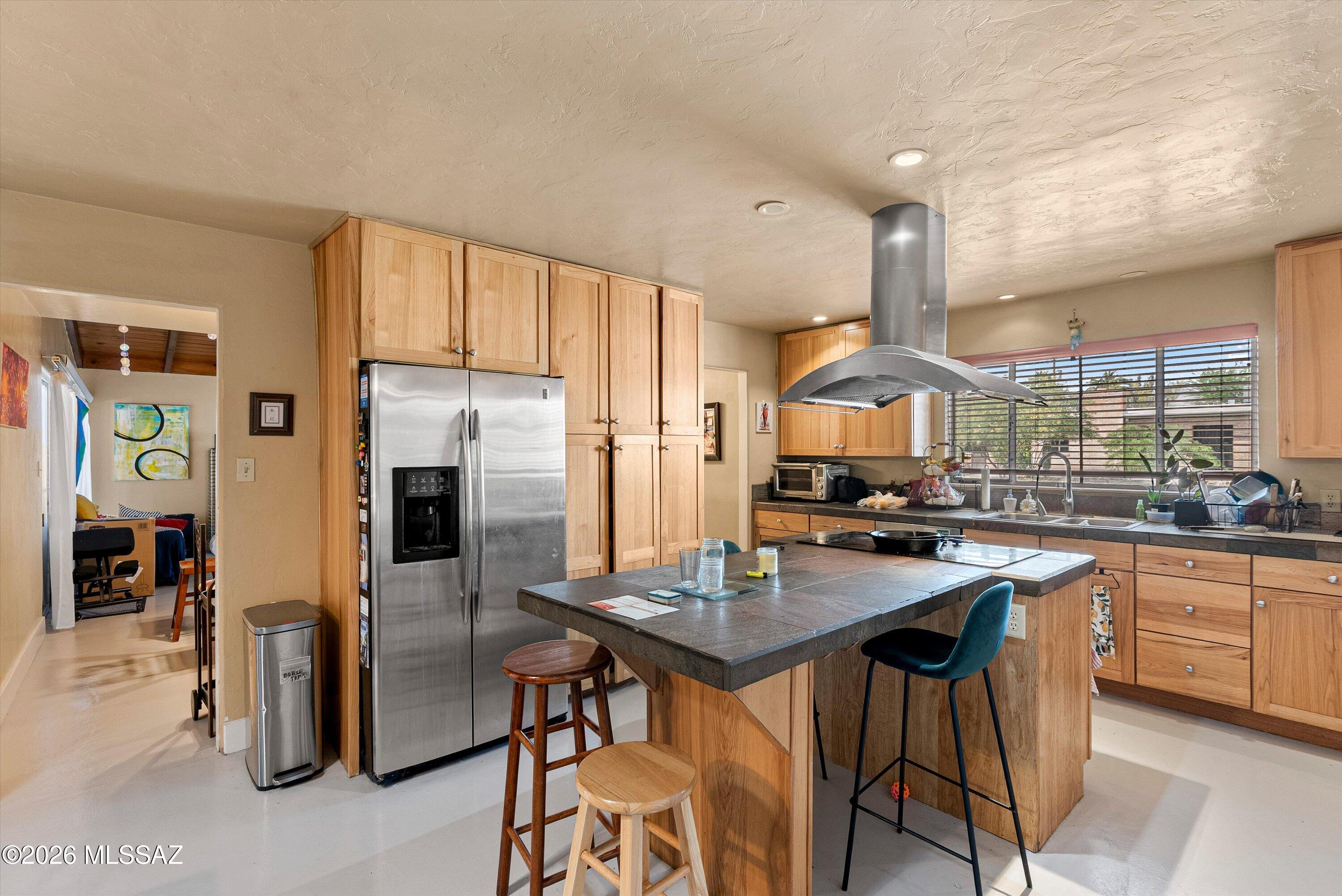 2934 East Exeter Street Tucson, AZ 85716 - Photo 7 of 20 a kitchen with stainless steel appliances granite countertop a stove a refrigerator a sink a dining table and chairs with wooden floor
