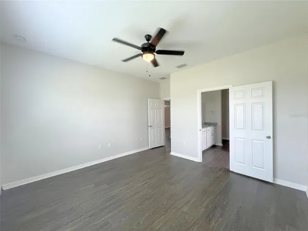 an empty room with wooden floor ceiling fan and windows