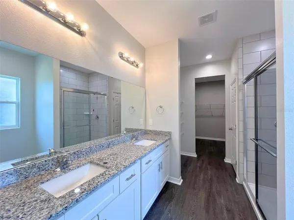 a bathroom with a granite countertop double vanity sink and mirror