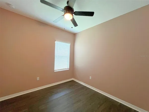 an empty room with wooden floor ceiling fan and windows