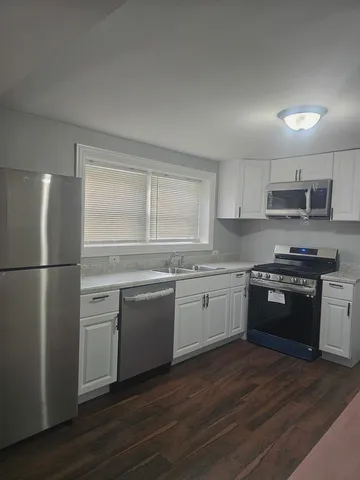a kitchen with granite countertop a refrigerator stove top oven and sink