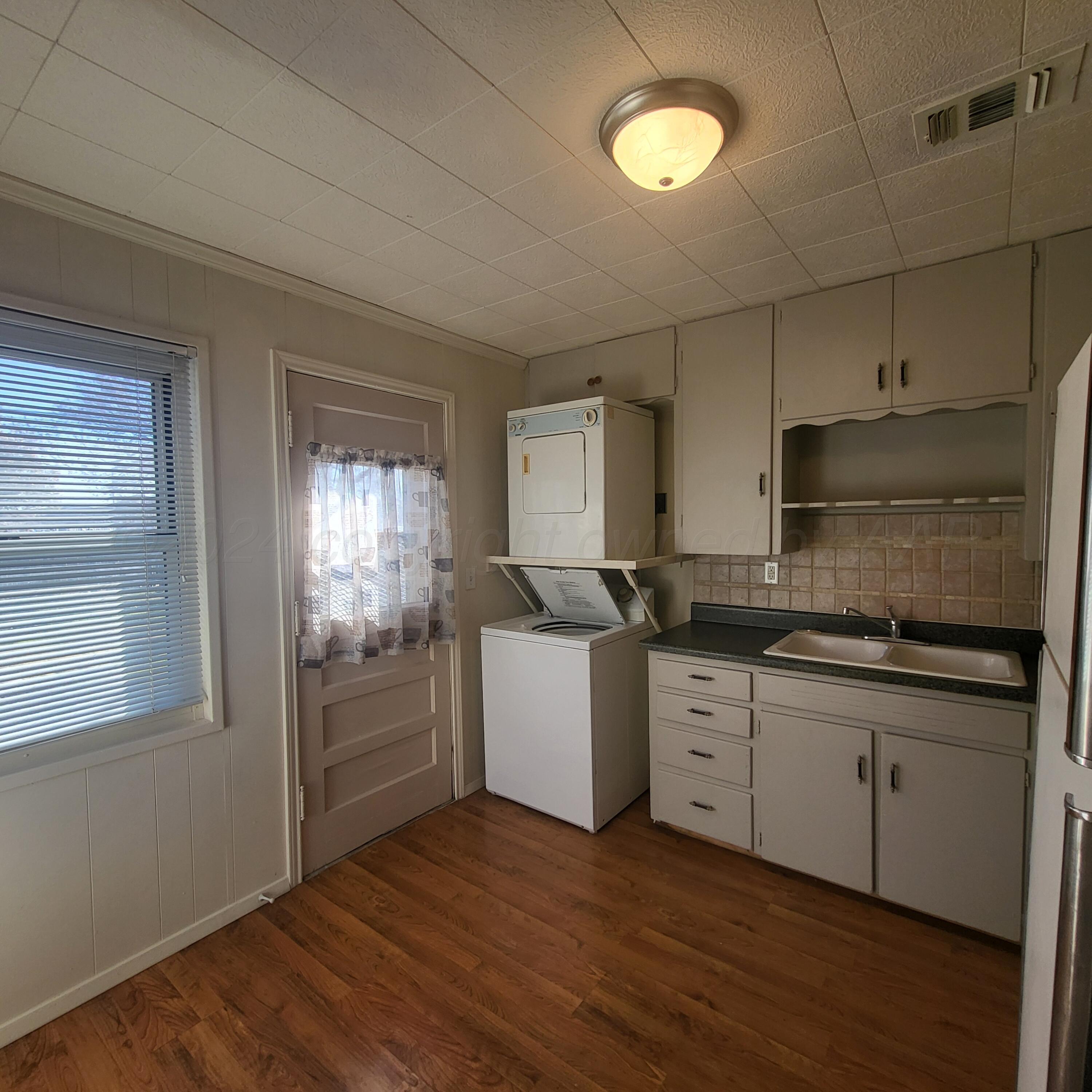 4619 South Hughes Street Amarillo, TX 79110 - Photo 7 of 15 a kitchen with a sink cabinets wooden floor and stainless steel appliances