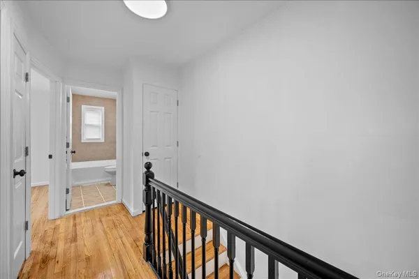 a view of a hallway with wooden floor and a bathroom