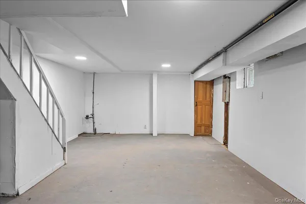 a view of an empty room with wooden floor and stairs