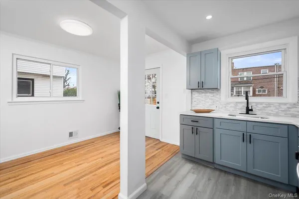 a view of a kitchen with a sink wooden cabinets and entryway