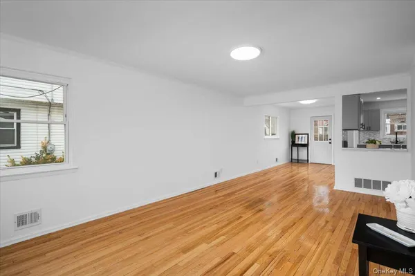 a view of kitchen and empty room with wooden floor and windows