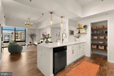 a large white kitchen with stainless steel appliances granite countertop a stove a sink a dining table and chairs