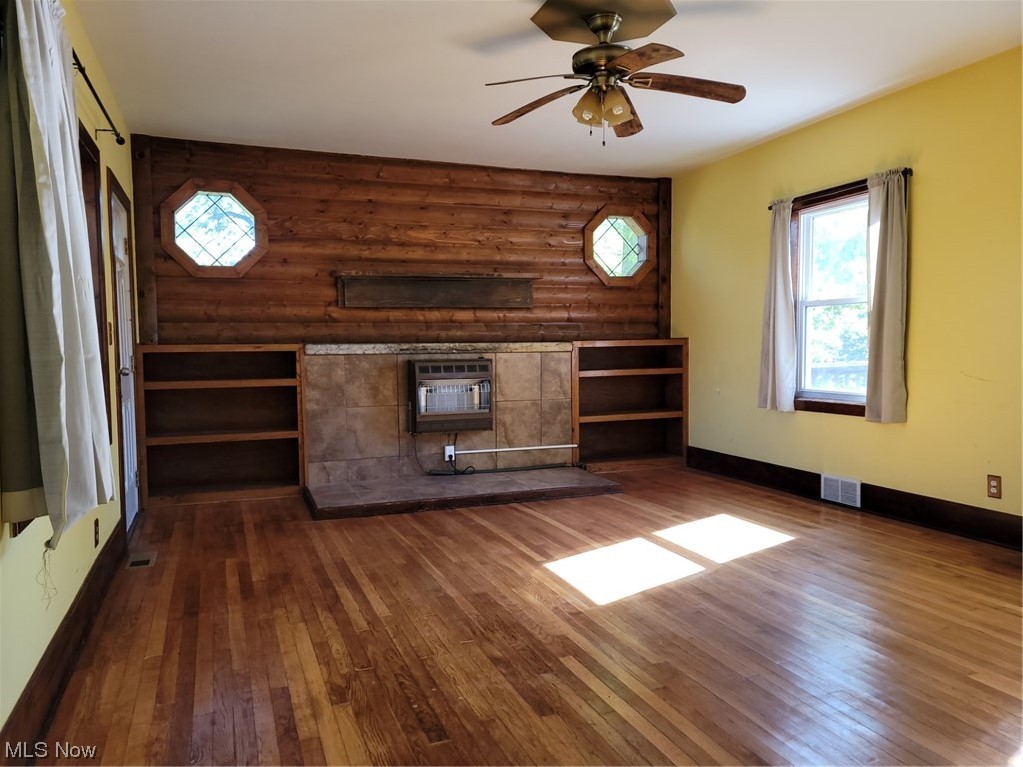 22922 Putney Ridge Road Quaker City, OH 43773 - Photo 16 of 31 Hardwood floored living room featuring a wall mounted air conditioner, log walls, and ceiling fan