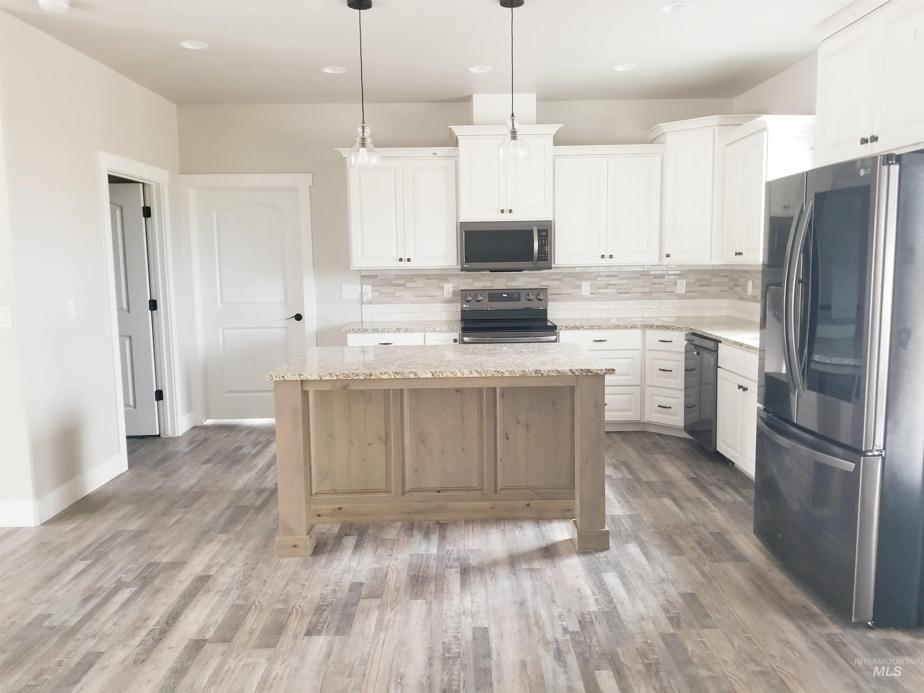 212 Fafnir Drive Kimberly, ID 83341 - Photo 9 of 36 Kitchen with appliances with stainless steel finishes, backsplash, light stone countertops, white cabinetry, and hanging light fixtures