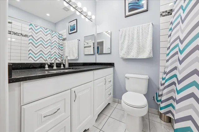 a bathroom with a granite countertop sink a toilet and a mirror