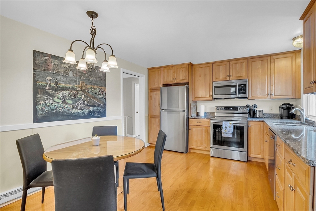 75 Nonantum Street Newton, MA 02458 - Photo 12 of 41 a kitchen with granite countertop a stove a sink a kitchen island with chairs and wooden floor