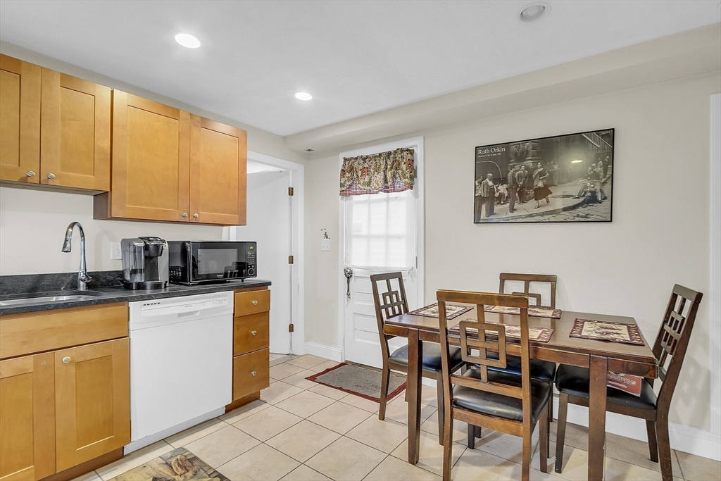 75 Nonantum Street Newton, MA 02458 - Photo 26 of 41 a kitchen with stainless steel appliances granite countertop a stove top oven a sink a dining table and chairs with wooden floor