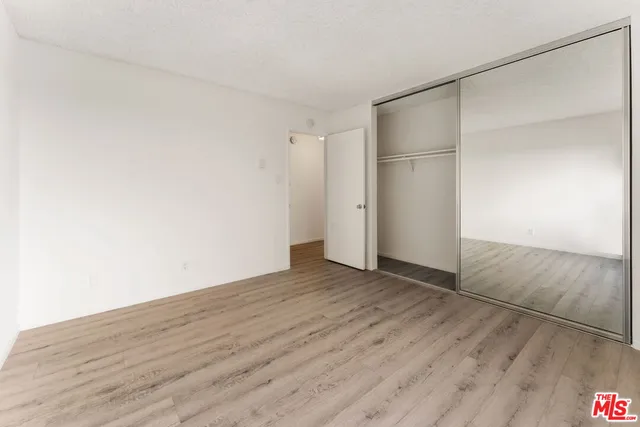 a view of an empty room with wooden floor and closet