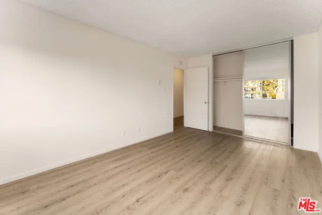 a view of an empty room and window with wooden floor