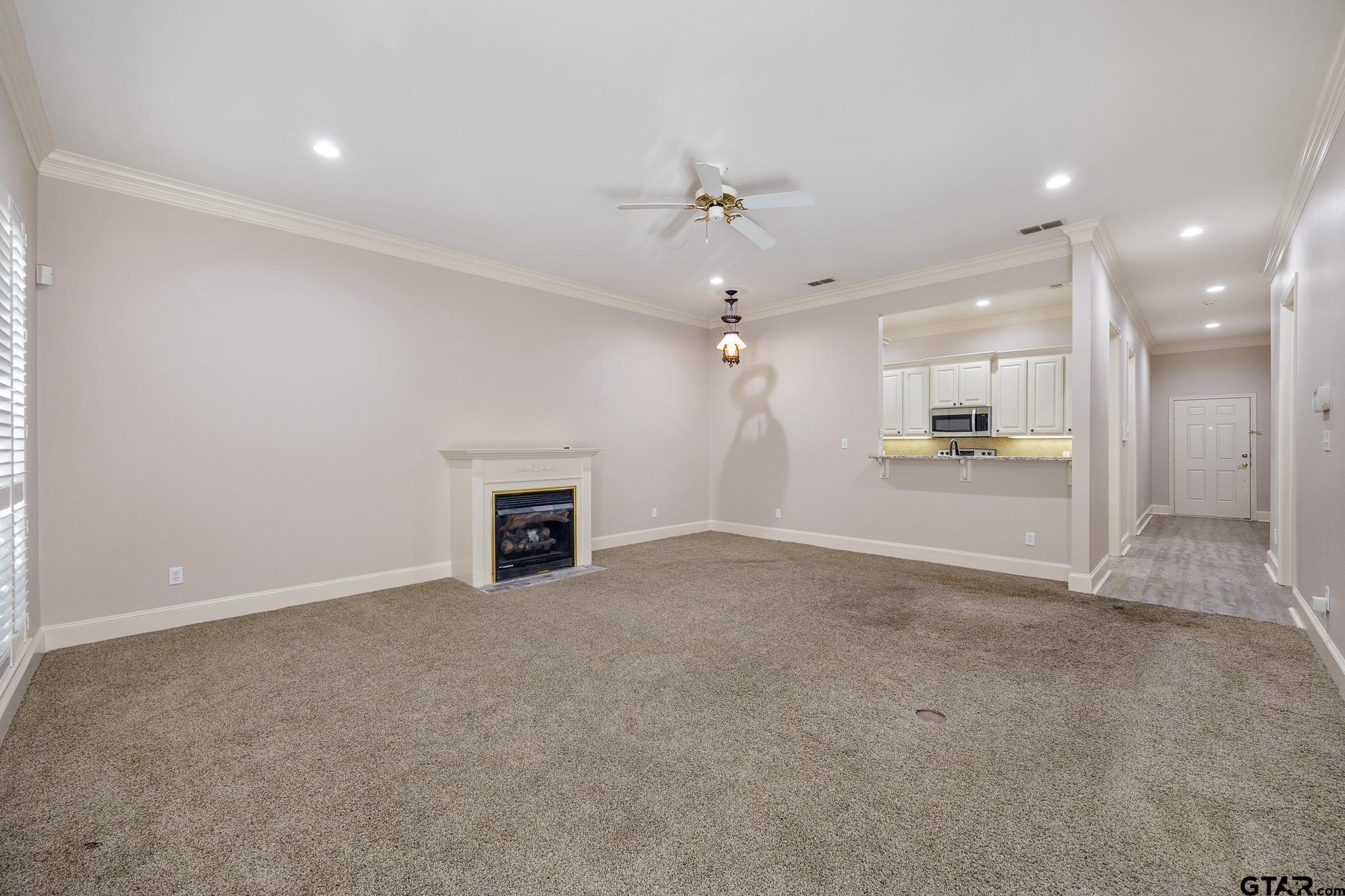 2431 Homestead Lane Tyler, TX 75701 - Photo 14 of 26 an empty room with a fireplace and fan