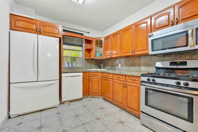 a kitchen with stainless steel appliances granite countertop a refrigerator a stove and a microwave