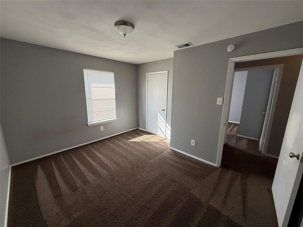 1714 Short Street, Unit D Cleburne, TX 76033 - Photo 7 of 9 Carpeted room featuring neutral gray walls, white trim, a single window, and a flush-mount ceiling light fixture