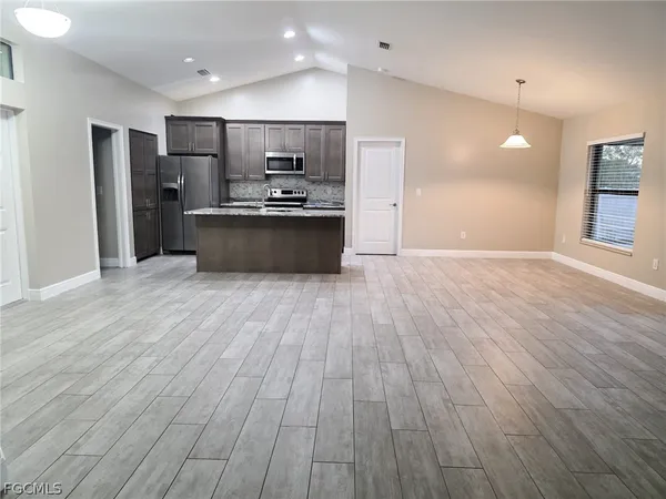 a large kitchen with stainless steel appliances a large counter top a sink and a refrigerator