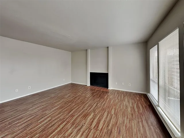 a view of empty room with wooden floor and fireplace