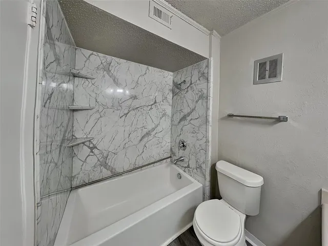a white toilet sitting next to a bath tub and a shower