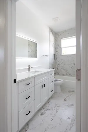 a bathroom with a double vanity sink toilet mirror and bathtub
