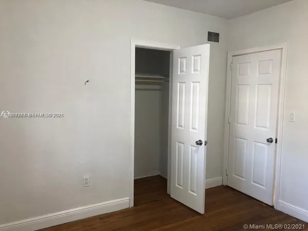 an empty room with wooden floor & closet area