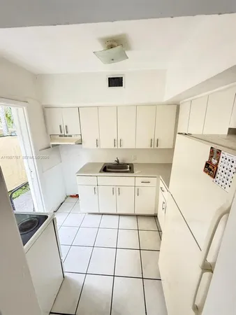 a kitchen with a sink a stove and white cabinets