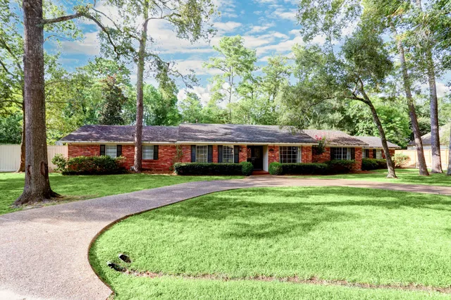 a front view of a house with a garden and trees