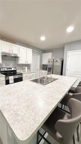a kitchen with kitchen island a stove a sink a counter top space and a center island
