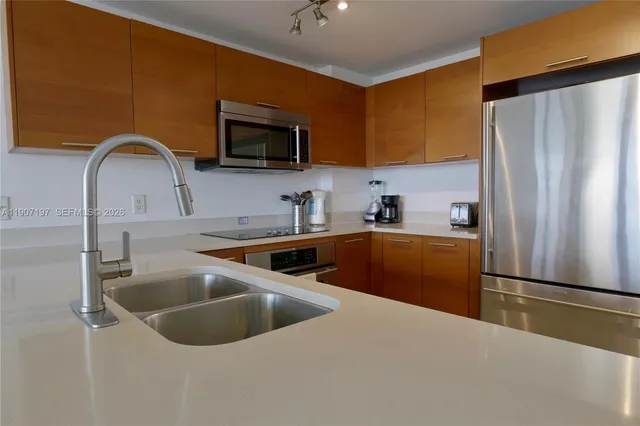 a kitchen with stainless steel appliances granite countertop a sink a refrigerator and a stove top oven with wooden floor