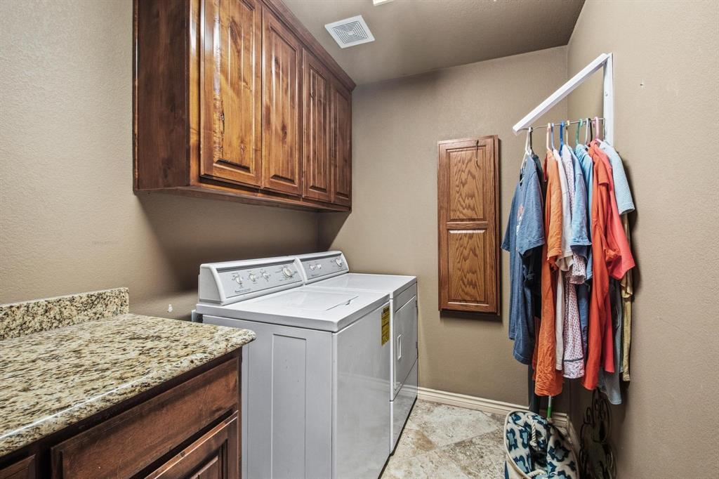 112 Knight Court Springtown, TX 76082 - Photo 19 of 26 Laundry area featuring wood cabinetry, stone-finish countertop, and tile flooring