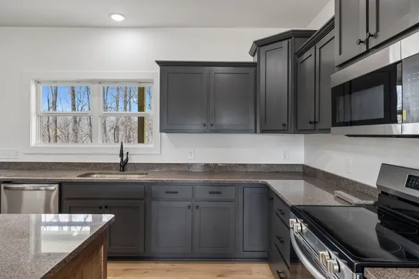 a kitchen with stainless steel appliances granite countertop a sink stove and microwave