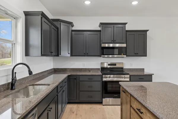 a kitchen with stainless steel appliances granite countertop a stove a sink and a microwave