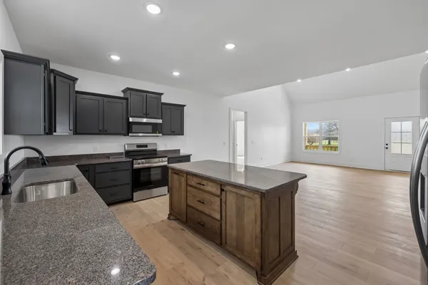 a kitchen with stainless steel appliances granite countertop a sink dishwasher stove and oven with wooden floor