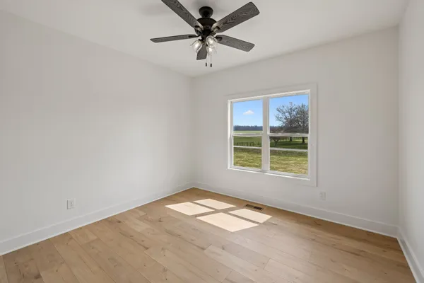 an empty room with a window and a fan