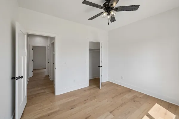 an empty room with wooden floor closet and windows