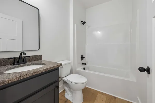 a bathroom with a granite countertop toilet a sink and a bathtub
